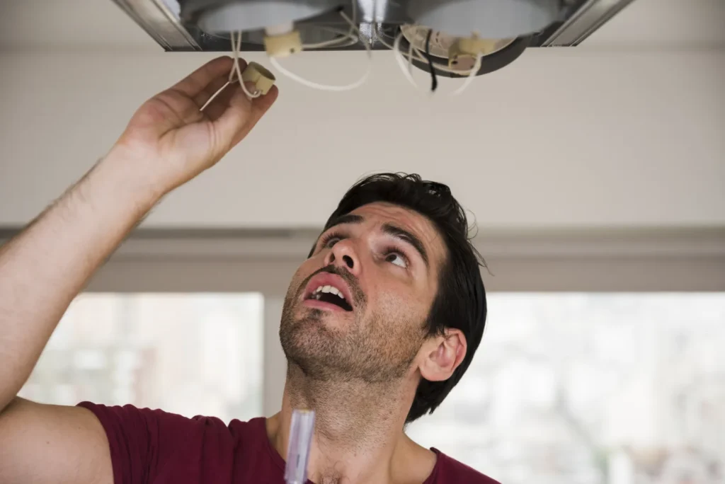 Electricista instalando el soporte de una lámpara de techo