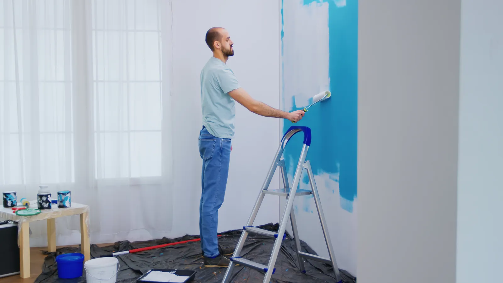 Pintor pintando con rodillo la pared de un apartamento en Bogotá