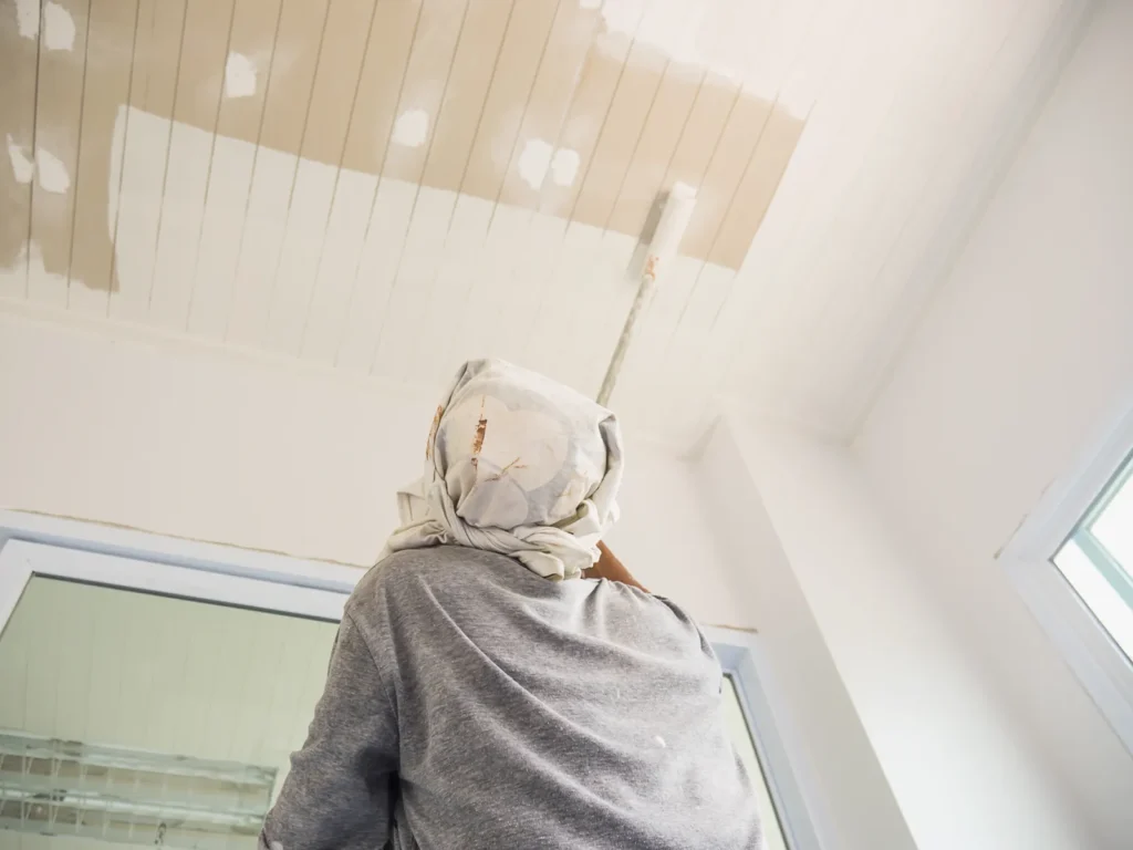 Pintor pintando el techo de una habitación con rodillo