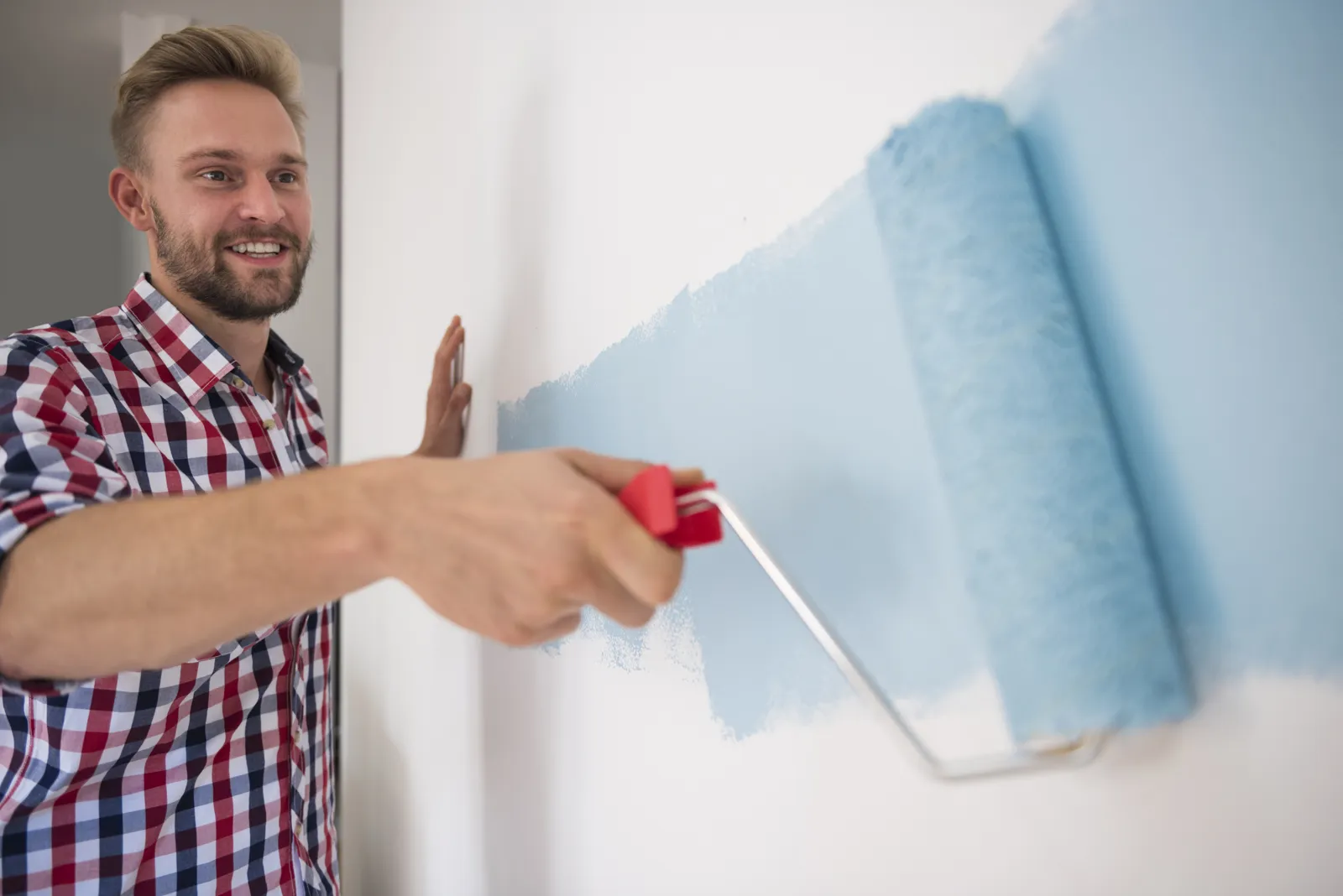 Pintor pintando una pared con rodillo en un apartamento de Medellín