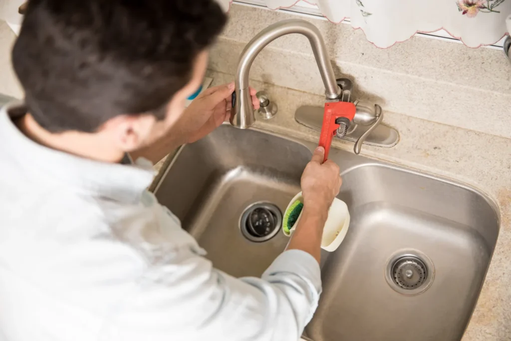 Plomero ajustando una llave de agua con una llave de tubo